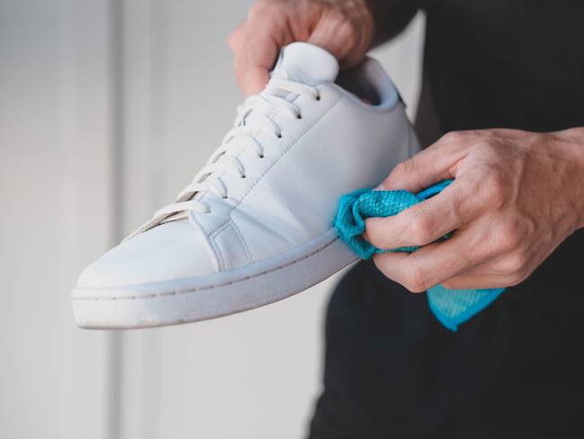 Persona limpiando zapatos blancos con un trapo imagen de referencia. Foto: Getty Images.