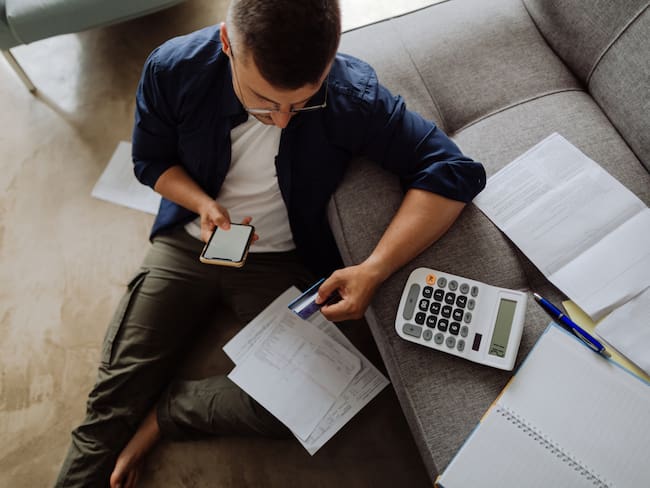 Hombre haciendo cuentas de sus facturas con calculadora (Getty Images)