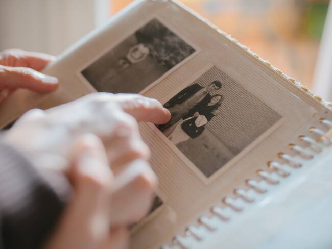 Close up view of a grandmother sharing memories and stories with her granddaughter while showing her an old family photo album. Memories and family concept.