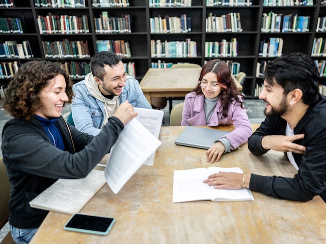 Estudiantes universitarios compartiendo en la biblioteca (Foto vía Getty Images)