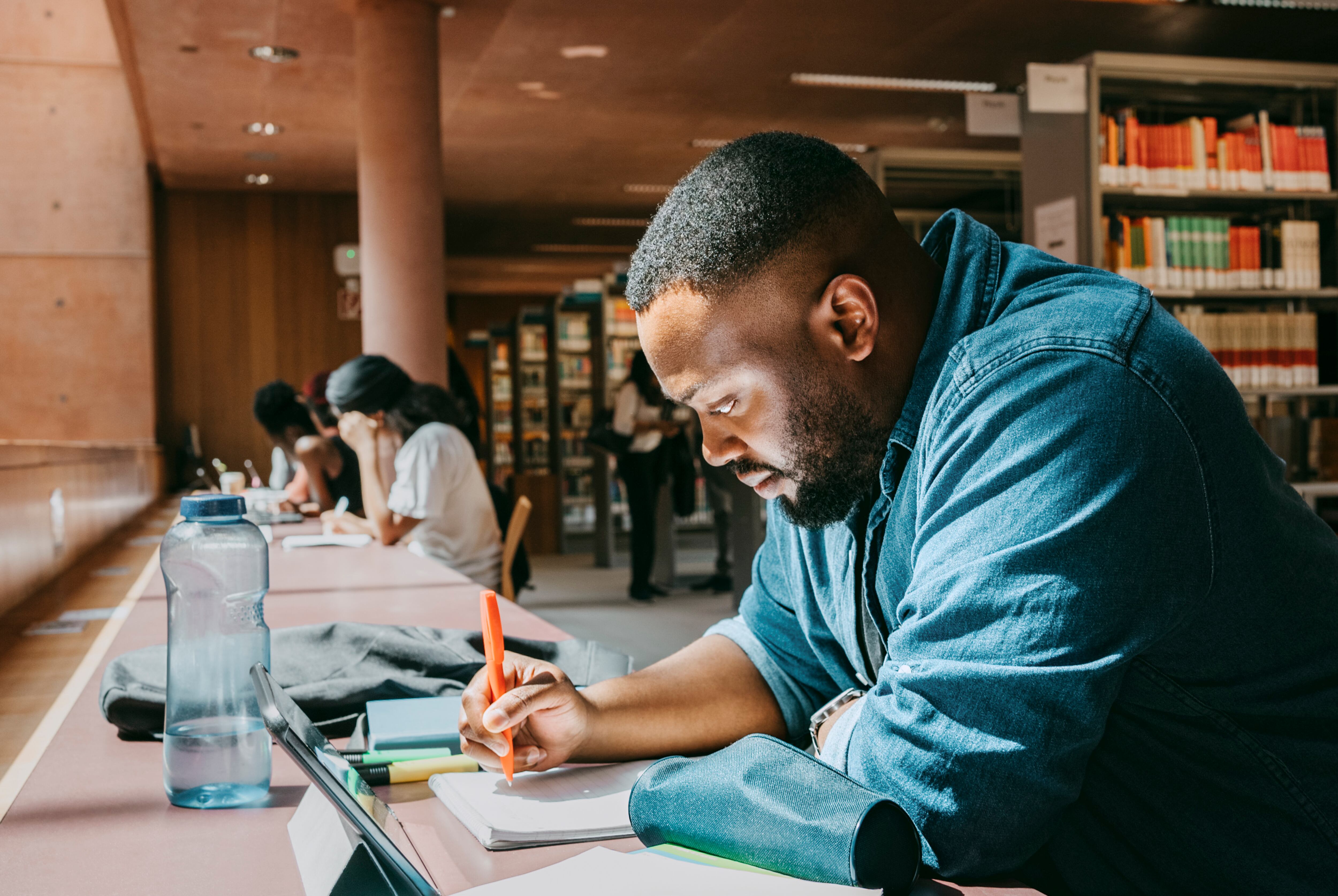 Estudiante de posgrado en una biblioteca escribiendo en un cuaderno / Foto: GettyImages