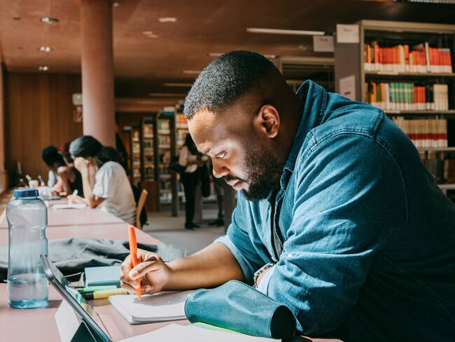 Estudiante de posgrado en una biblioteca escribiendo en un cuaderno / Foto: GettyImages