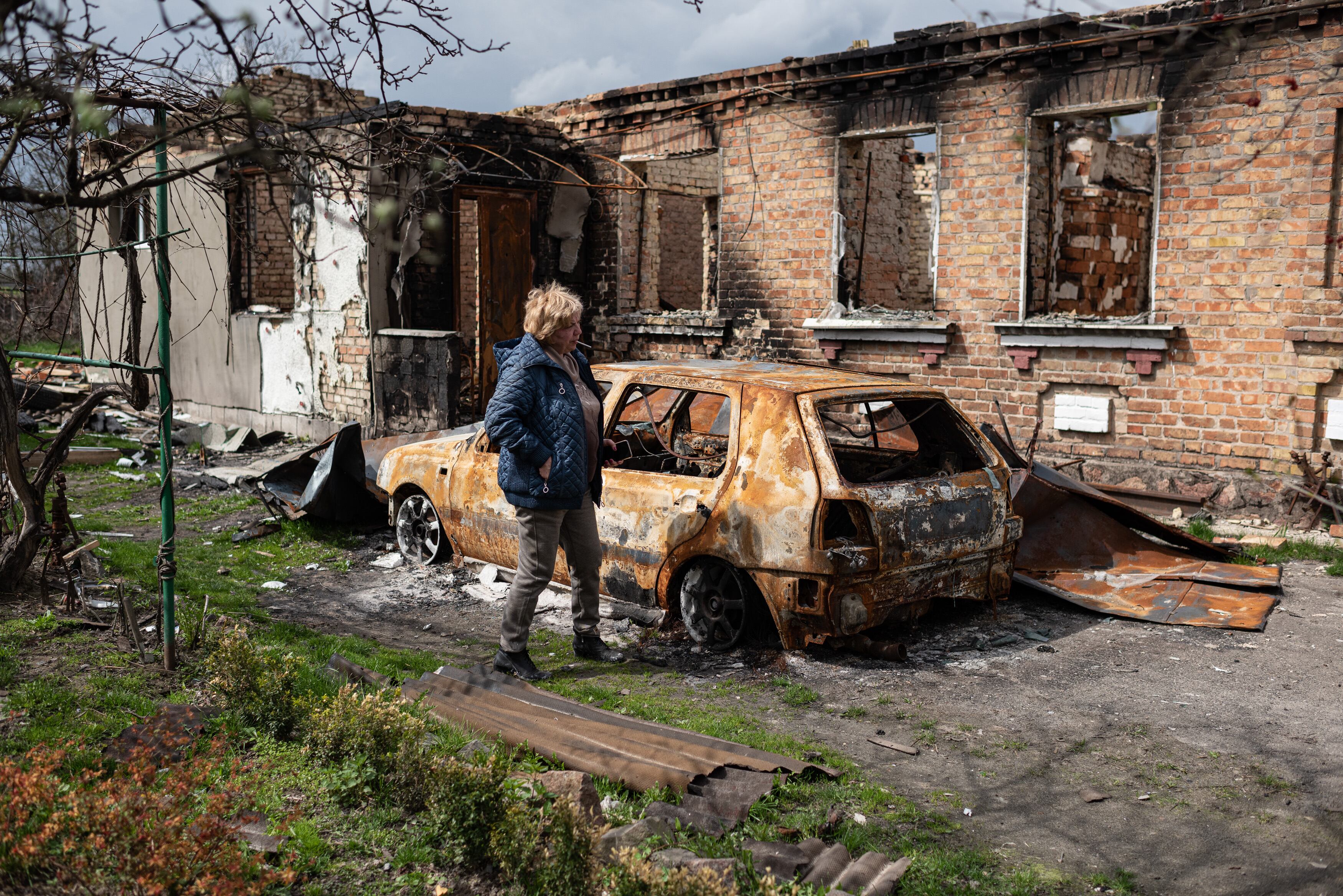 OZERA, UKRAINE - APRIL 25: Inna, 53, walks by the burnt car of her son next to her burnt house on April 25, 2022 in Ozera, Ukraine. The towns around Kyiv are continuing a long road to what they hope is recovery, following weeks of brutal war as Russia made its failed bid to take Ukraine's capital. As Russia concentrates its attack on the east and south of the country, residents of the Kyiv region are returning to assess the war's toll on their communities.  (Photo by Alexey Furman/Getty Images)