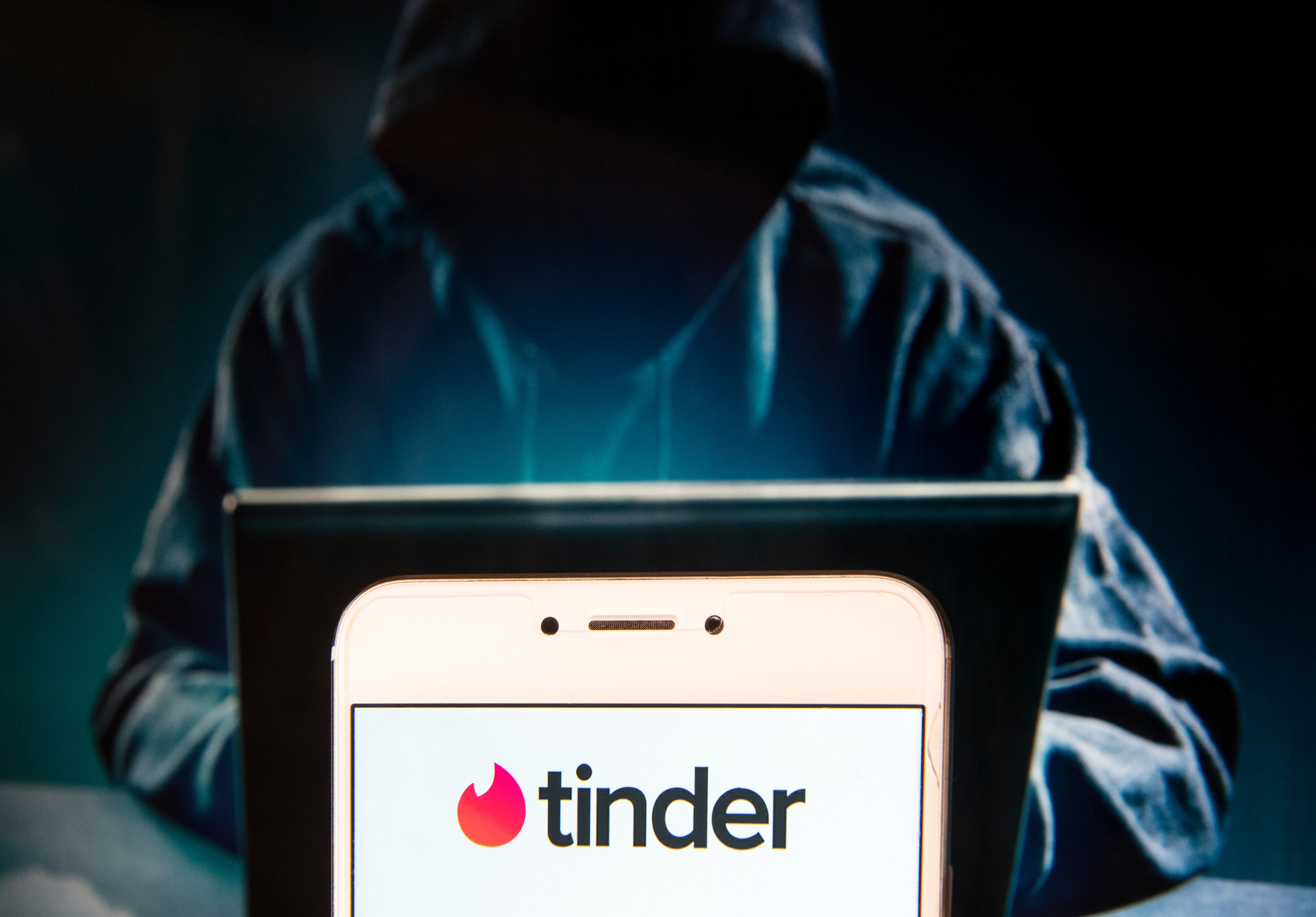 HONG KONG, CHINA - 2018/11/27: In this photo illustration, the Mobile dating app Tinder logo is seen displayed on an Android mobile device with a figure of hacker in the background. (Photo Illustration by Miguel Candela / SOPA Images/SOPA Images/LightRocket via Getty Images)