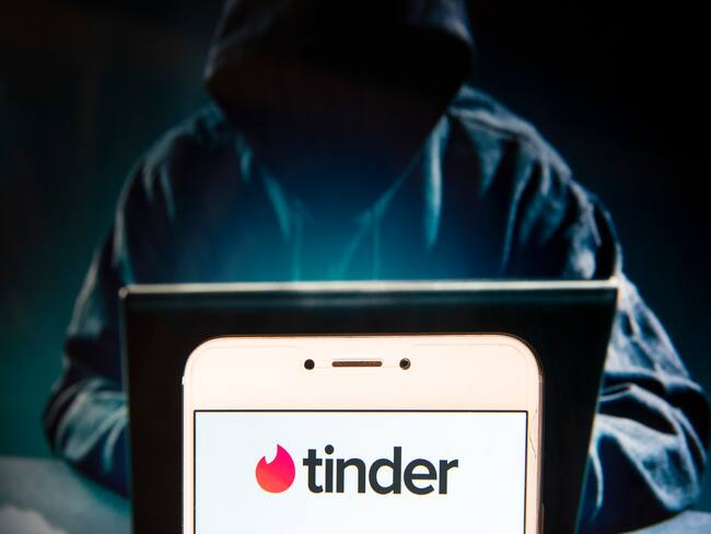 HONG KONG, CHINA - 2018/11/27: In this photo illustration, the Mobile dating app Tinder logo is seen displayed on an Android mobile device with a figure of hacker in the background. (Photo Illustration by Miguel Candela / SOPA Images/SOPA Images/LightRocket via Getty Images)