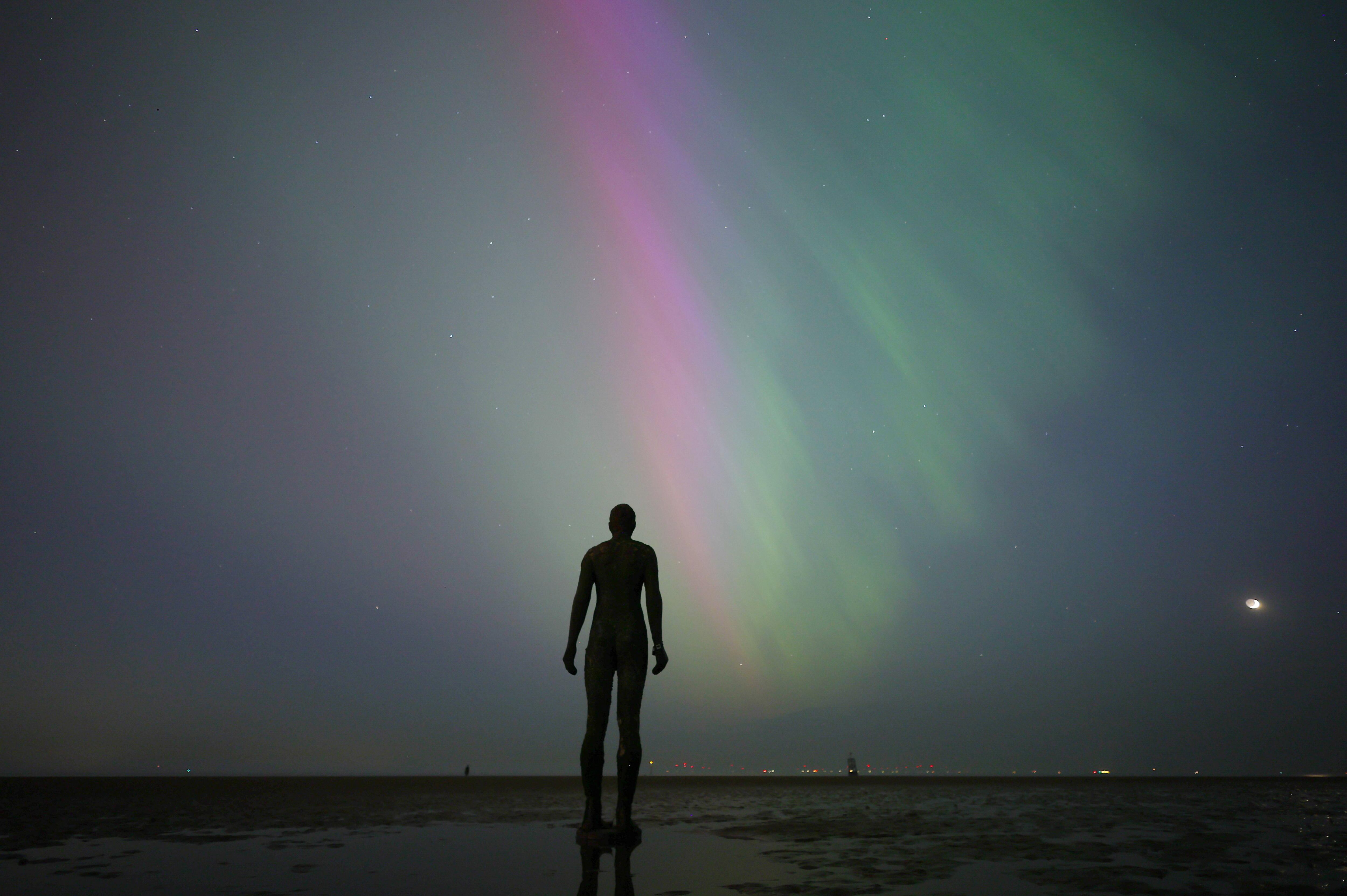 Fotografía de una aurora boreal frente a la escultura "Another Place' de Anthony Gormley en Crosby, (Reino Unido). EFE/EPA/ADAM VAUGHAN