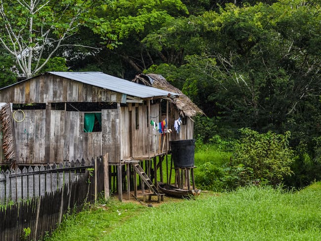 Wooden house on stilts infant of lush granary jungle with a clothes drying on a rope on the side of the house. Photo: Getty Images
