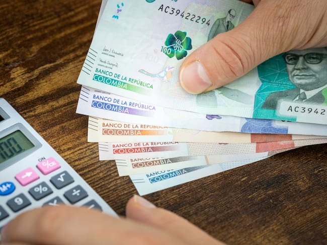 Hombre haciendo cuenta con billetes colombianos (Getty Images)