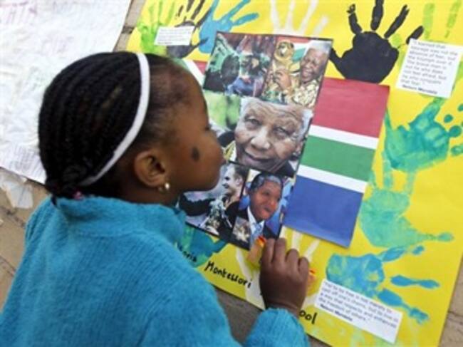 na niña besa una fotografía del expresidente sudafricano Nelson Mandela en un mural colgado a la entrada del hospital de Pretoria. Foto: EFE.