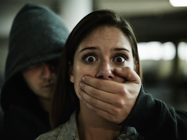 A terrified young woman held captive by a man with his hand over her mouth