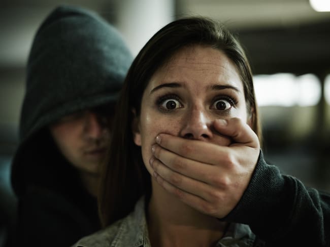 A terrified young woman held captive by a man with his hand over her mouth