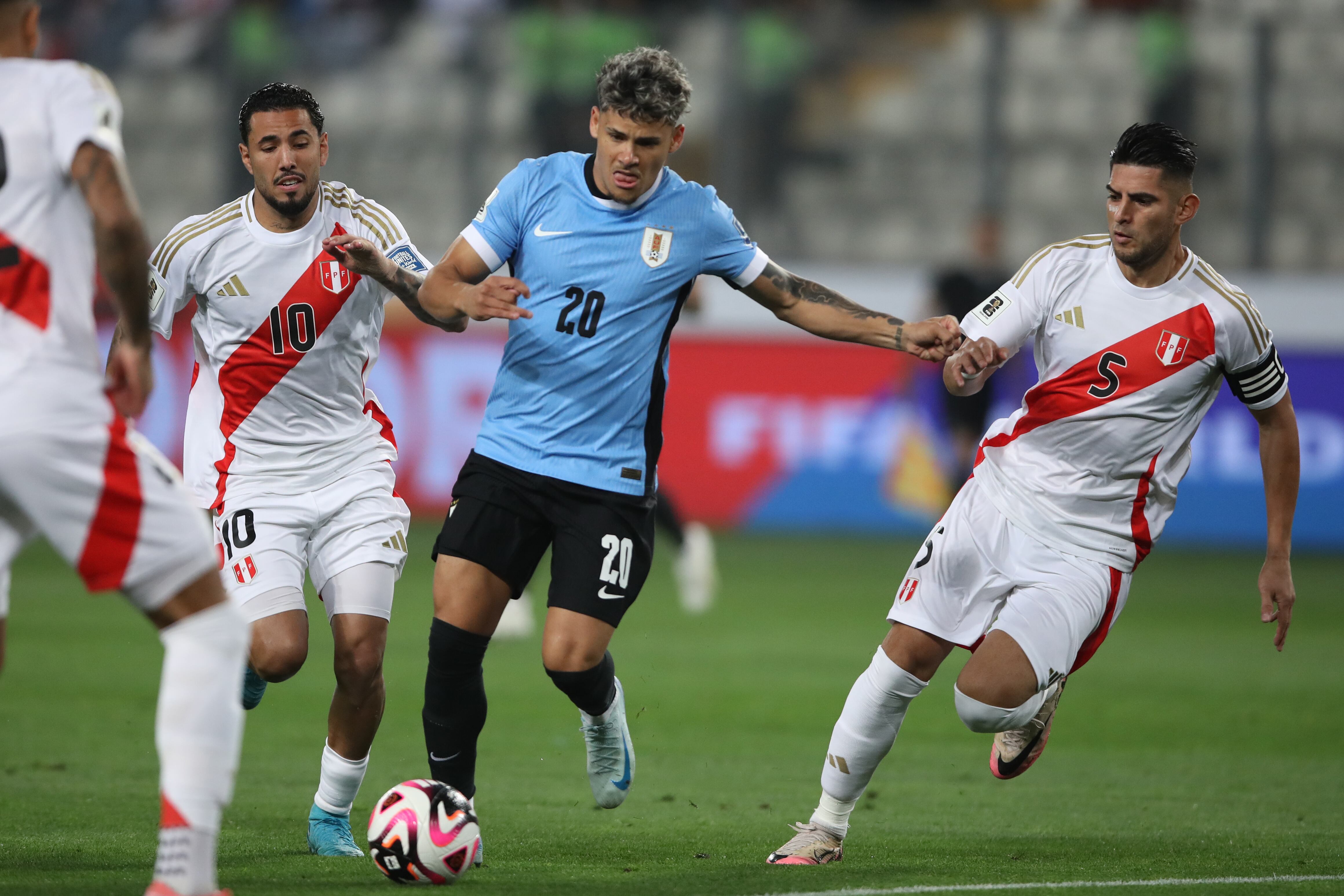 . LIMA (PERÚ), 11/10/2024.- Sergio Peña (i) y Carlos Augusto Zambrano (d) de Perú disputan un balón con Maximiliano Araújo (c) de Uruguay este viernes, en un partido de las eliminatorias sudamericanas para el Mundial de 2026 entre Perú y Uruguay en el estadio Nacional de Perú en Lima (Perú). EFE/ Paolo Aguilar