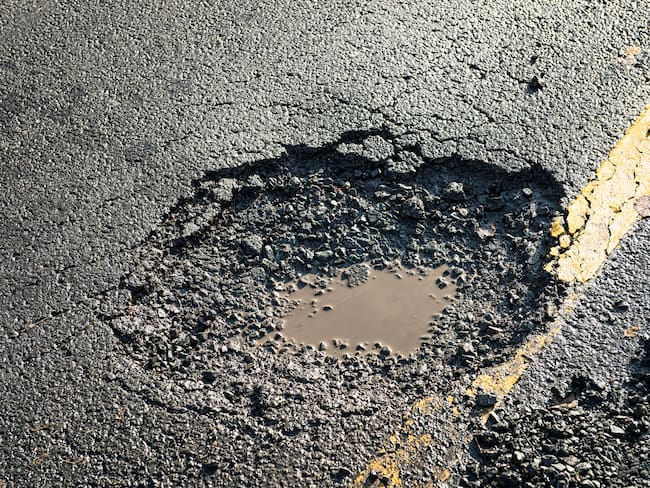 Close-up of the effects of road weathering and neglect - a deep pot hole causing a danger to drivers.