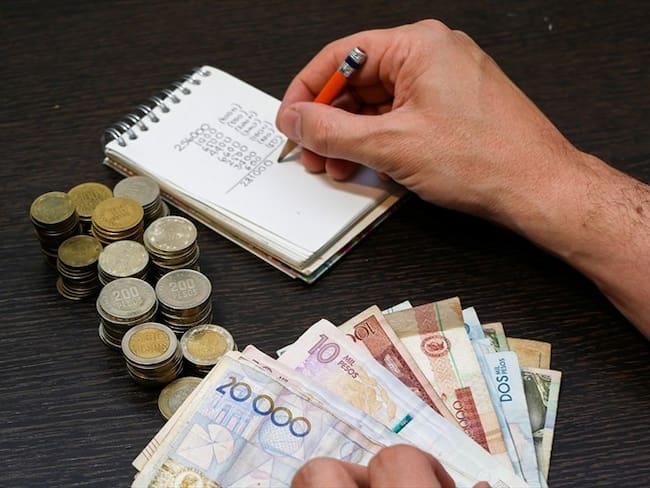 Persona haciendo cuentas con dinero colombiano. Foto: Getty Images: Ricardo Vallejo / EyeEm