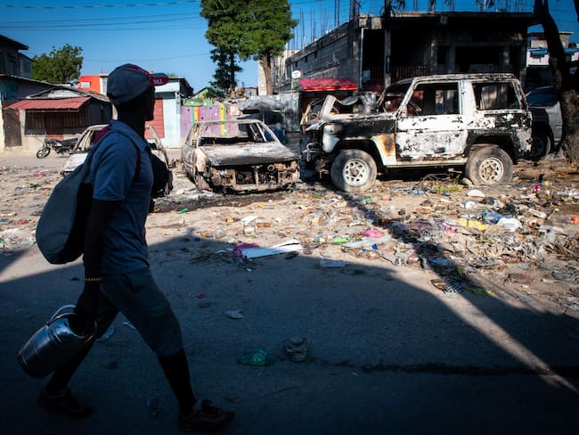 PUERTO PRÍNCIPE (HAITÍ), 09/03/2024.- Un hombre camina frente a vehículos incinerados, este sábado en Puerto Príncipe (Haití). Presuntos delincuentes fueron abatidos por la Policía Nacional de Haití durante un ataque al Palacio Nacional la noche del viernes en Puerto Príncipe, orquestado por la coalición de bandas armadas &quot;Vivre Ensemble&quot;, según publicaron este sábado medios locales. EFE/ Johnson Sabin