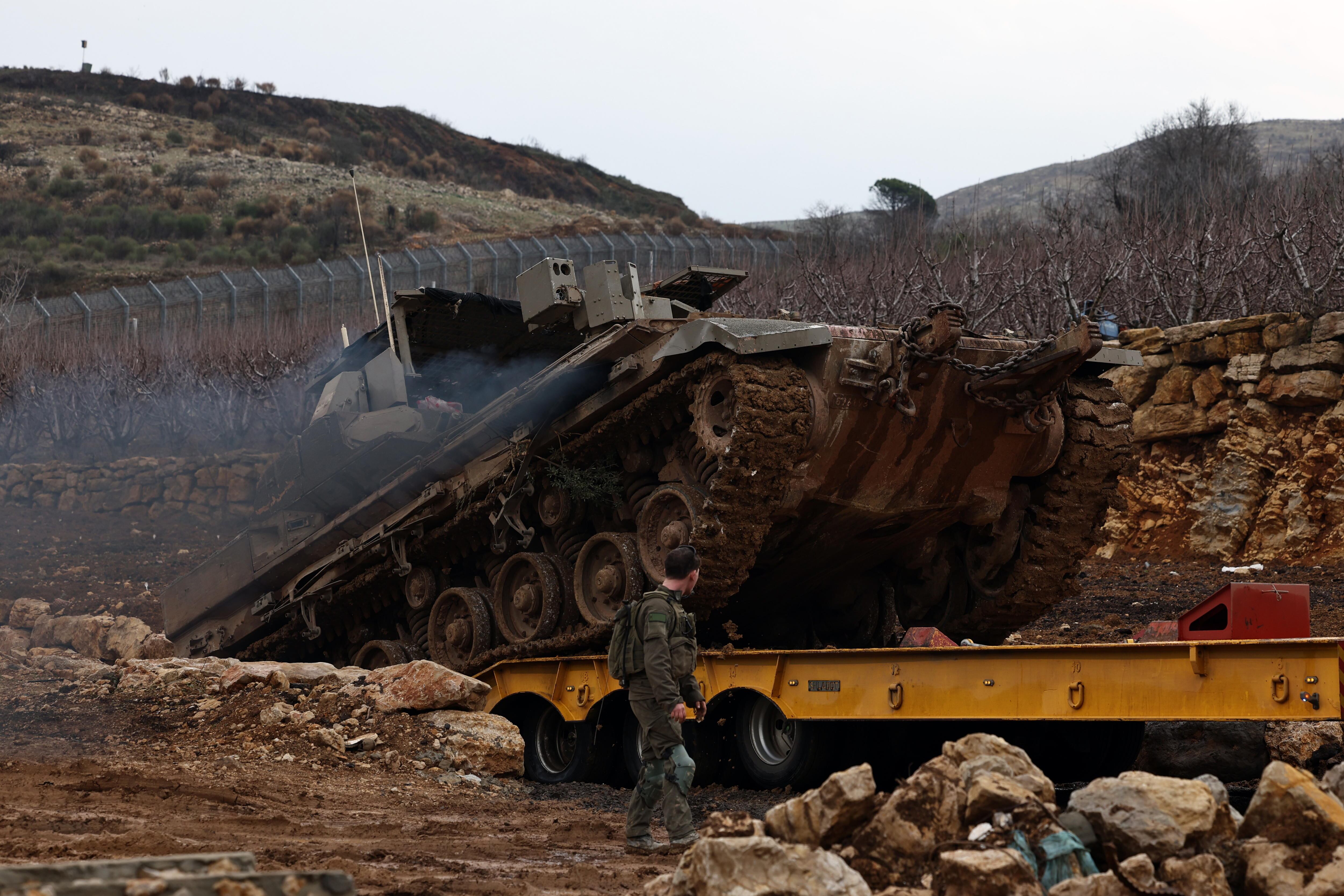 Un soldado israelí da instrucciones a un vehículo blindado de transporte de tropas que sube a un camión mientras salen de la zona de amortiguación, en la frontera entre Israel y Siria, en los Altos del Golán anexionados por Israel. EFE/EPA/ATEF SAFADI