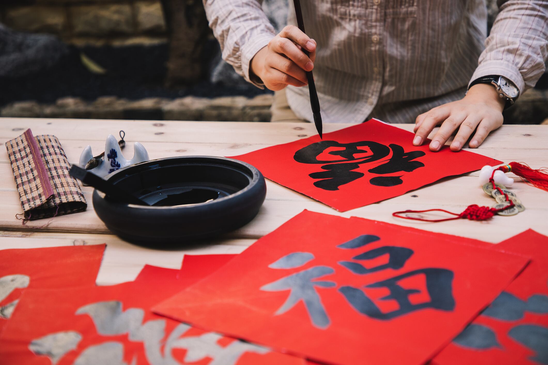 Mujer asiática escribiendo el carácter 'Fu' que significa fortuna y buena suerte para Año Nuevo (Getty Images)