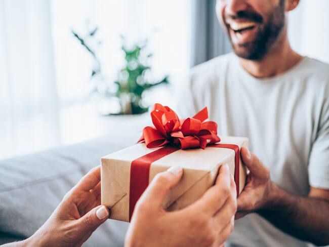 Joven alegre recibiendo un regalo de su pareja (Foto vía Getty Images)