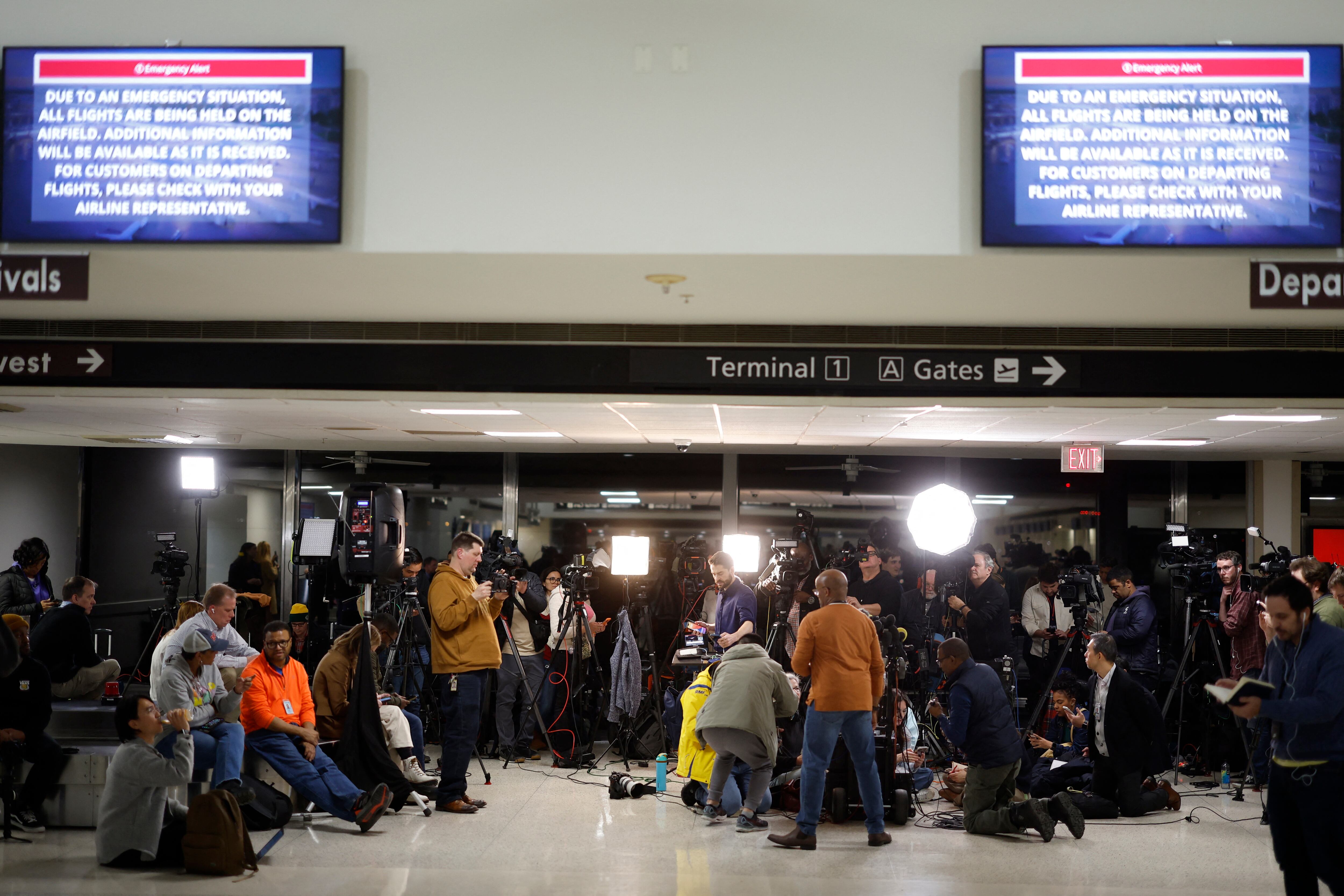 Pantallas de información en el Aeropuerto Nacional Reagan muestran instrucciones de emergencia mientras periodistas esperan una rueda de prensa, después de que un avión se estrellara en el río Potomac en las afueras de Washington, el 30 de enero de 2025. AFP