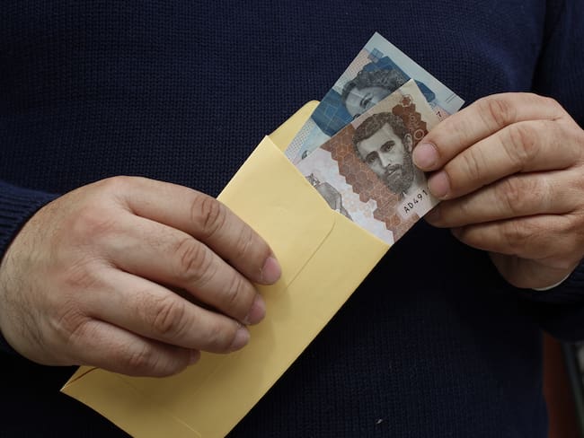 hands of a man keeping colombian banknotes in a paper envelope