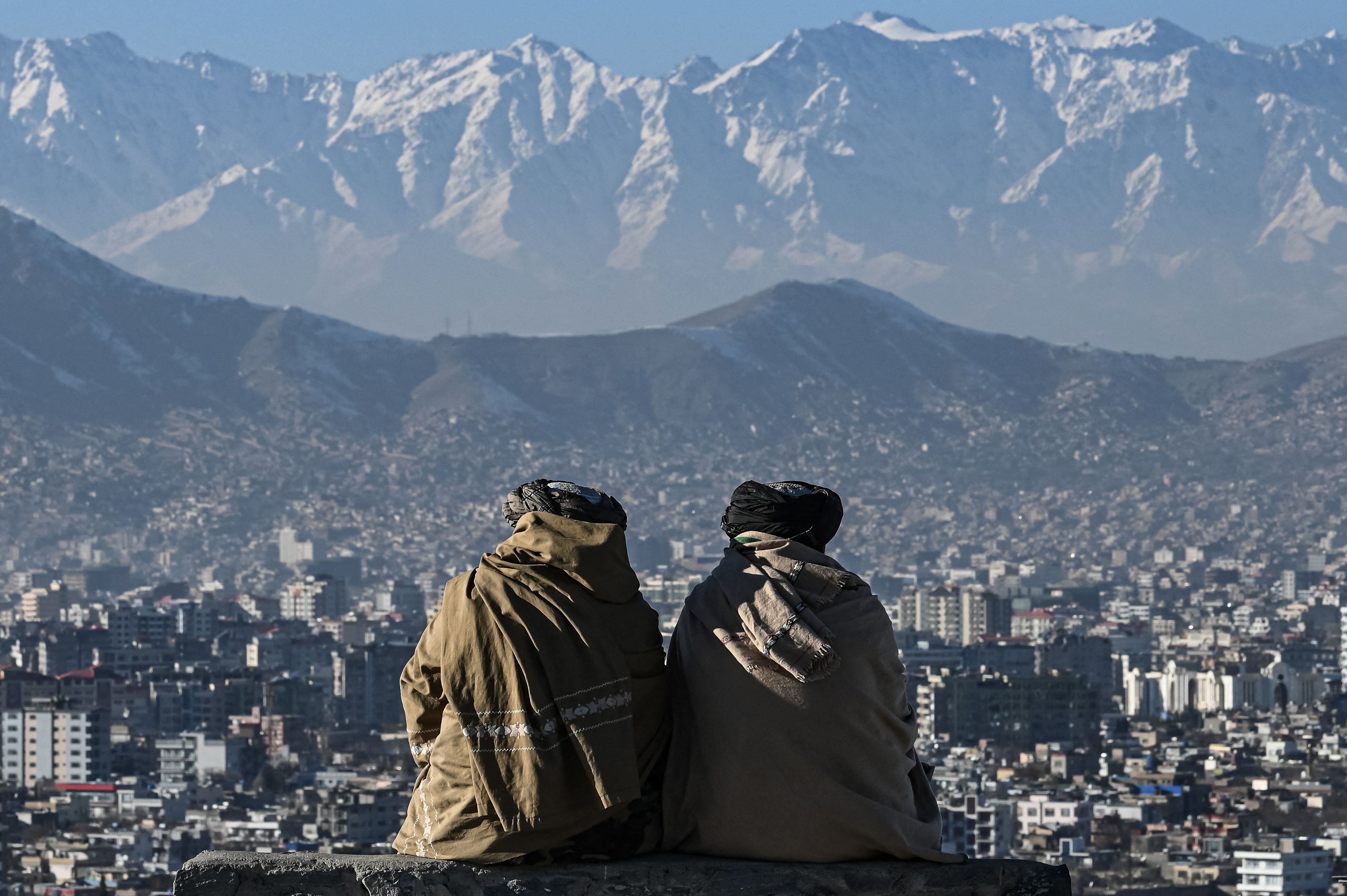 Members of the Taliban sit overlooking the Kabul city at the Wazir Akbar Khan hill in Kabul on January 20, 2022. (Photo by Mohd RASFAN / AFP) (Photo by MOHD RASFAN/AFP via Getty Images)