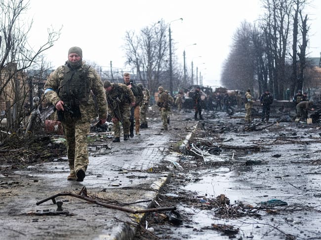BUCHA, UKRAINE - 2022/04/03: Ukrainian soldiers inspect the wreckage of a destroyed Russian armored column on the road in Bucha, a suburb north of Kyiv. As Russian troops withdraw from areas north of Ukraine's capital city of Kyiv, Ukrainian forces and the media found evidence of significant numbers of civilian casualties. The Ukrainian authorities are calling the killing of civilians in Bucha and other areas a war crime. (Photo by Matthew Hatcher/SOPA Images/LightRocket via Getty Images)