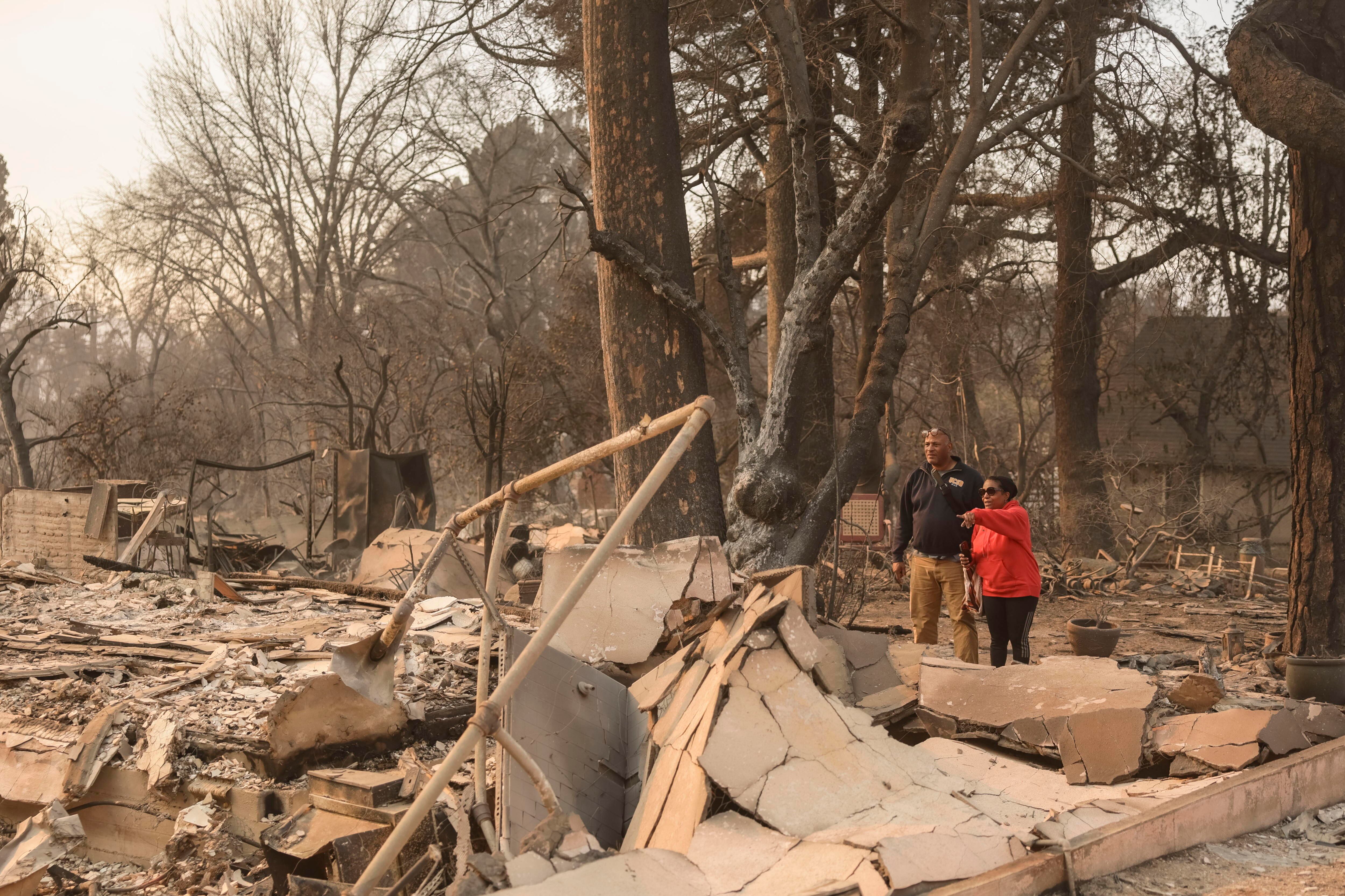 Altadena (Estados Unidos), 09/01/2025.- Varias personas observan los restos de una casa destruida por el incendio forestal de Eaton.