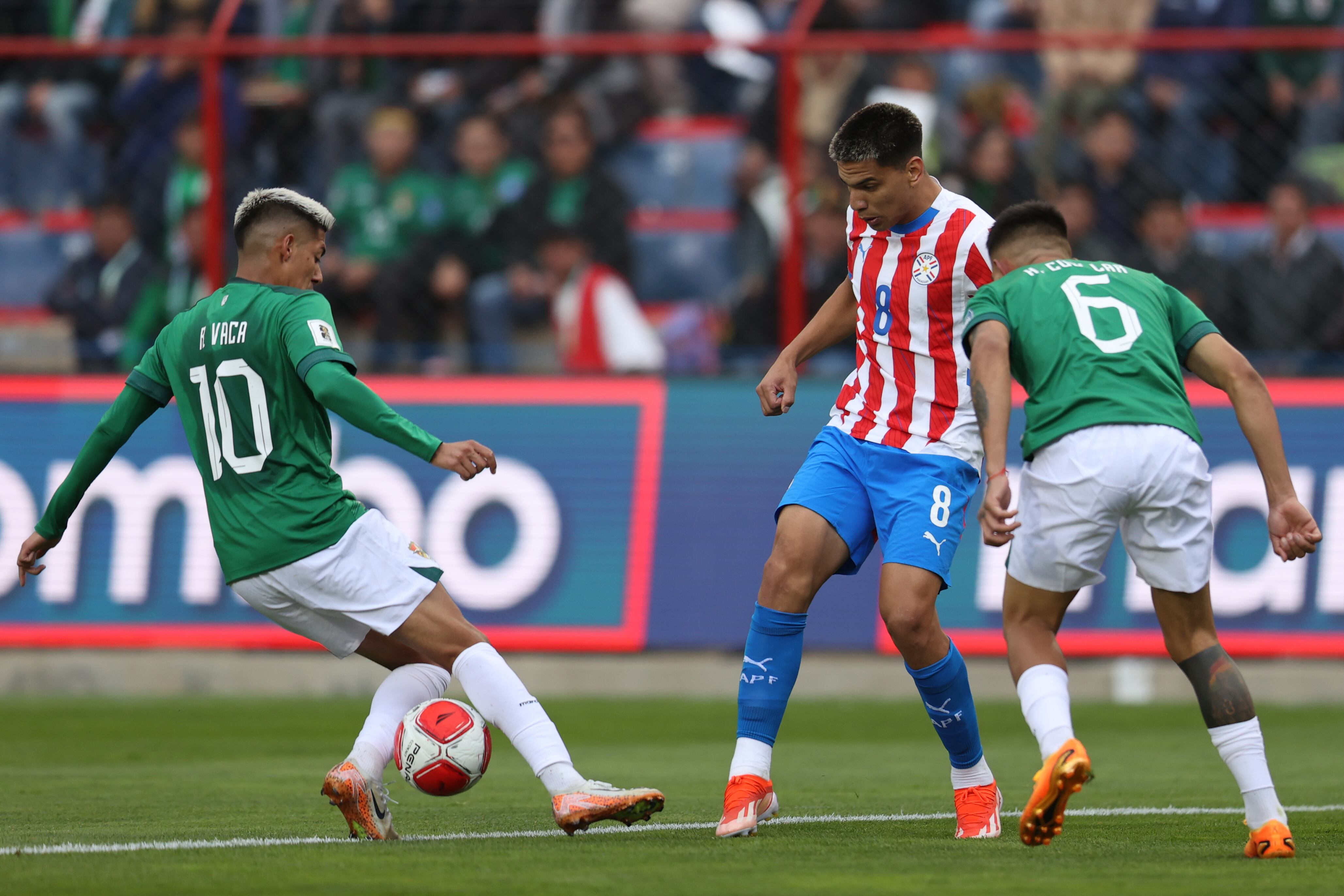 Ramiro Vaca (i) de Bolivia disputa un balón con Diego Gómez Amarilla (c) de Paraguay este martes, en un partido de las eliminatorias sudamericanas para el Mundial de 2026 entre Bolivia y Paraguay en el estadio Municipal de El Alto (Bolivia). EFE/ Luis Gandarillas