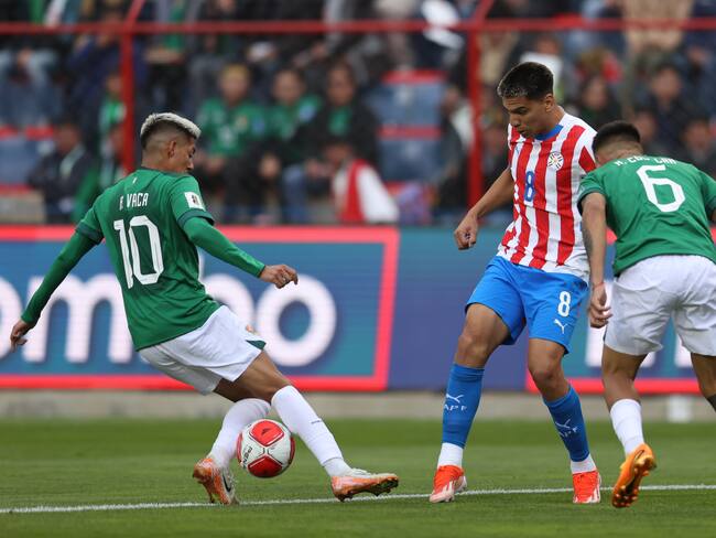 Ramiro Vaca (i) de Bolivia disputa un balón con Diego Gómez Amarilla (c) de Paraguay este martes, en un partido de las eliminatorias sudamericanas para el Mundial de 2026 entre Bolivia y Paraguay en el estadio Municipal de El Alto (Bolivia). EFE/ Luis Gandarillas