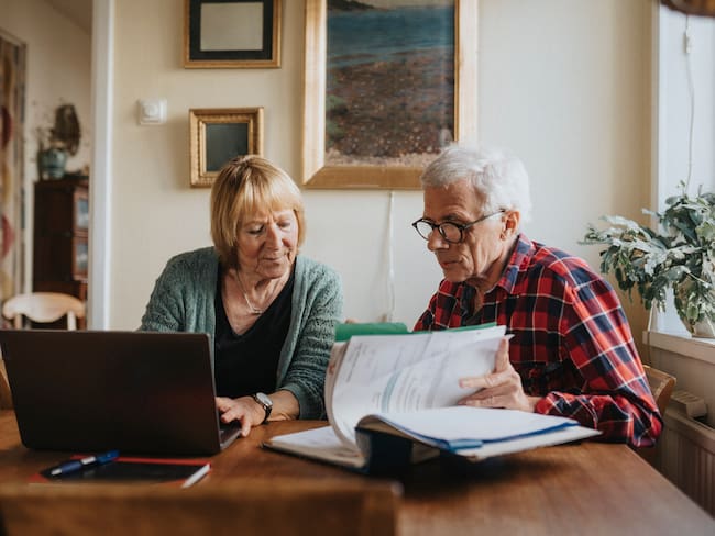 Pareja de adultos mayores usando computador para revisar su pensión (Foto vía GettyImages)