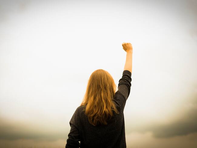 Rear view of woman with fist in the air.