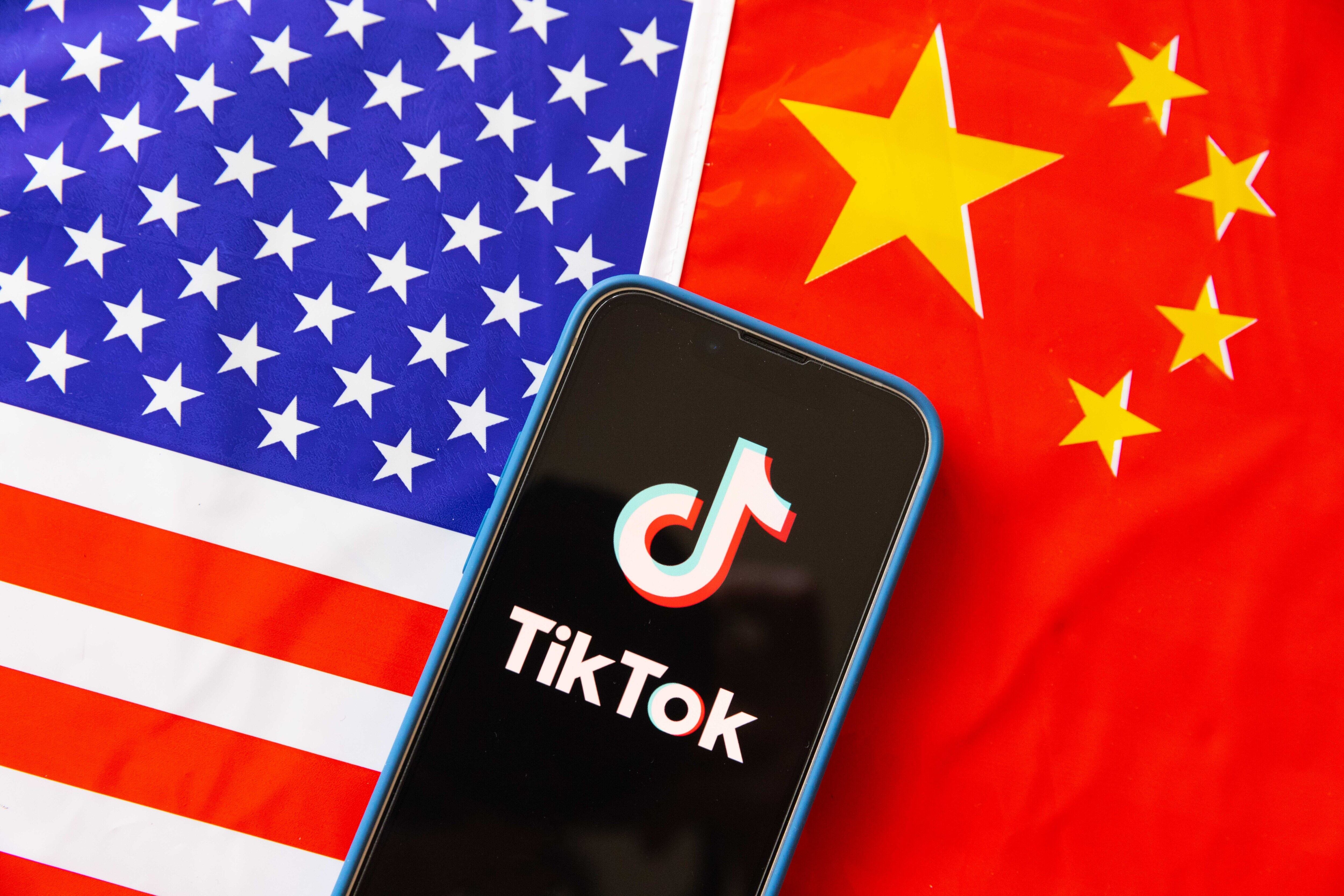 Ilustración: un teléfono móvil muestra el logotipo de TikTok con las banderas de Estados Unidos y la República Popular China al fondo. (Ilustración fotográfica de Stanislav Kogiku/SOPA Images/LightRocket vía Getty Images)
