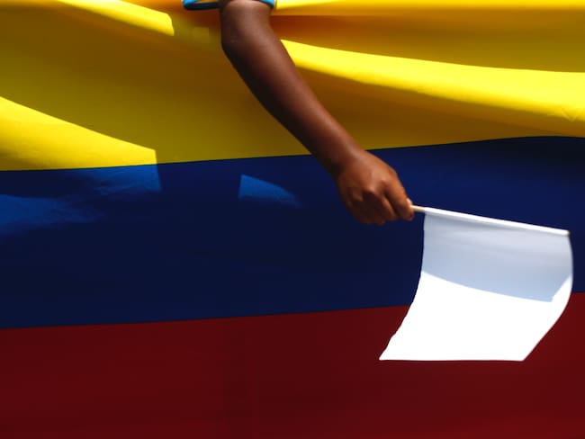 AME9288. CORINTO (COLOMBIA), 13/09/2023.- Una niña sostiene una bandera blanca sobre una bandera de Colombia durante un plantón organizado por autoridades municipales y estudiantes y profesores del colegio José María Obando, hoy, en Corinto (Colombia). Estudiantes, profesores y autoridades realizaron un plantón para pedir el cese de la violencia que azota el municipio de Corinto, norte del Cauca. El pasado 5 de septiembre durante un hostigamiento, esta institución educativa resultó afectada con cerca de 200 impactos de fusil, lo que obligó a trasladar a los estudiantes a otra sede educativa. EFE/ Ernesto Guzmán