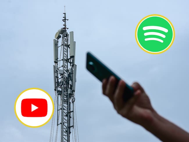 Persona usando los datos del celular al lado de una antena de telecomunicaciones. En los círculos, los logos de Spotify y YouTube (Fotos vía GettyImages)