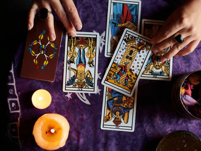 Close-up of a fortune teller reading tarot cards on a table with purple tablecloth