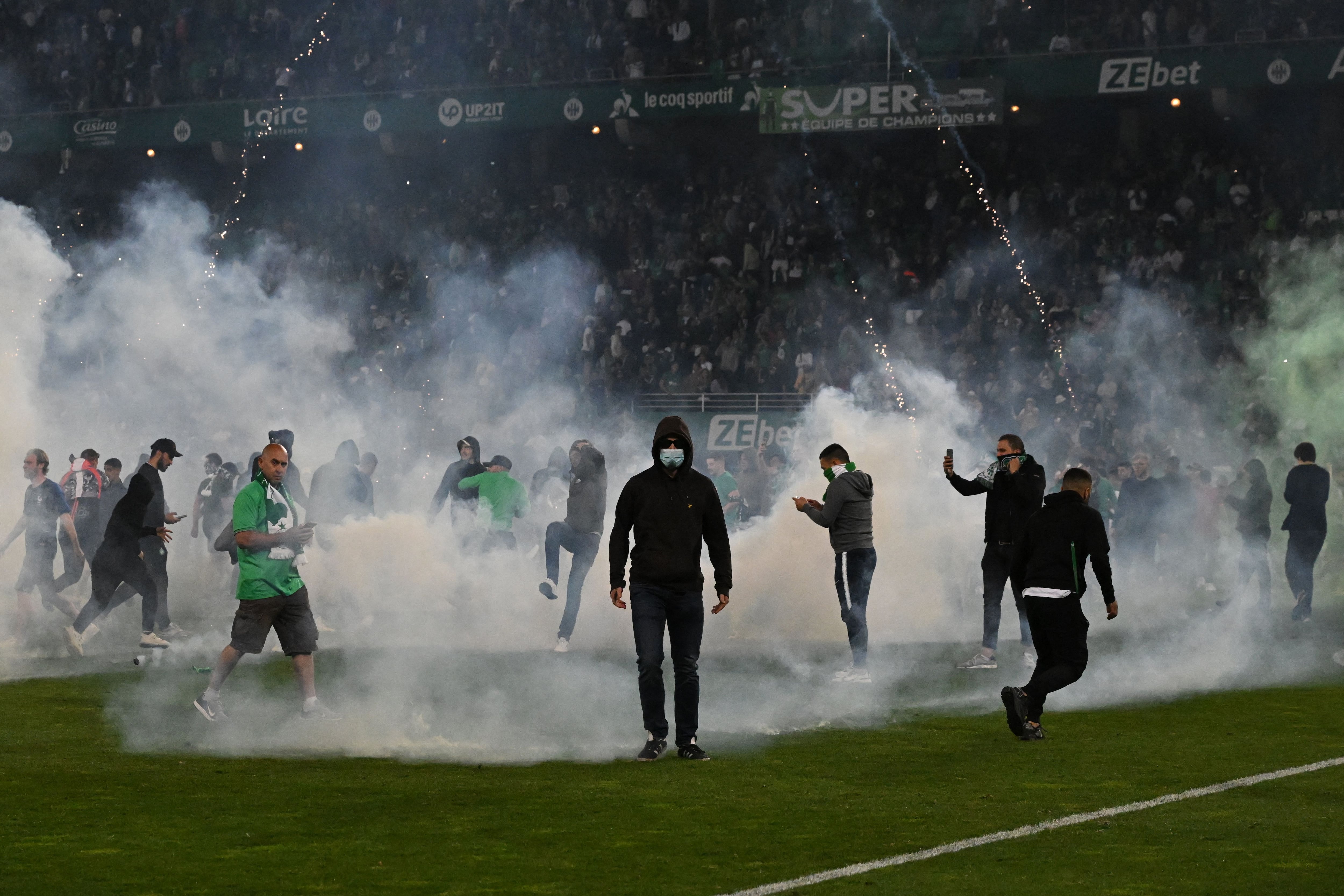 Saint-Etienne's fans invade the pitch through smoke after being defeated at the end of the French L1-L2 play-off second leg football match between AS Saint-Etienne and AJ Auxerre at the Geoffroy Guichard Stadium in Saint-Etienne, central-eastern France on May 29, 2022. (Photo by JEAN-PHILIPPE KSIAZEK / AFP) (Photo by JEAN-PHILIPPE KSIAZEK/AFP via Getty Images)