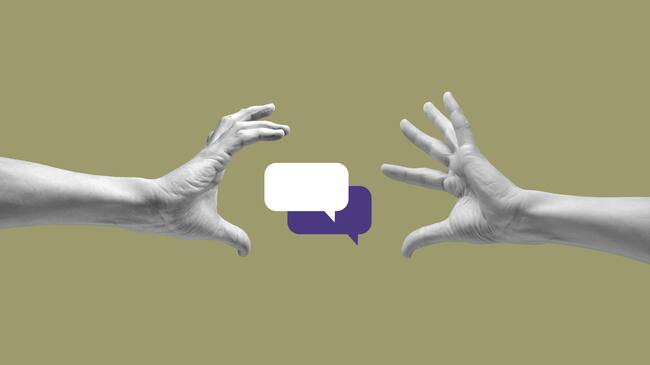 Speech bubbles between two human hands against khaki background.