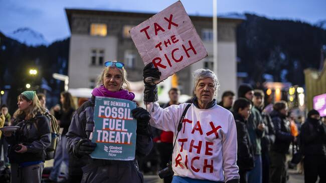 Davos (Switzerland), 19/01/2025.- Phil White of Patriotic Millionaires (R) holds a placard reading "Tax the rich" as he attend a demonstration before the annual meeting of the World Economic Forum (WEF) in Davos, Switzerland, 19 January 2025. The protest takes the demonstrators on a two-day hike from Kueblis to Davos. The World Economic Forum annual meeting brings together entrepreneurs, scientists, corporate and political leaders in Davos and takes place from January 20 to 24 in Davos. (Protestas, Suiza) EFE/EPA/MICHAEL BUHOLZER