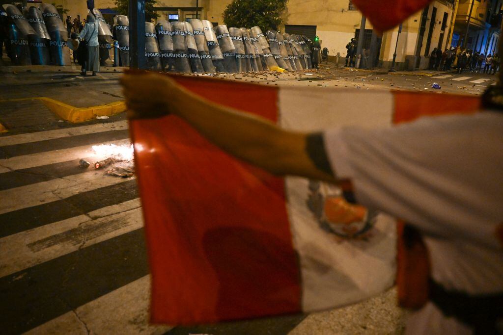 A demonstrator holds a Peruvian national flag in front of the riot police during a protest against the government of President Dina Boluarte in Lima on January 19, 2023. - Thousands of protesters began marching through Peru's capital Thursday to demand the president's resignation and fresh elections, following weeks of violent unrest that have left 44 people dead. (Photo by ERNESTO BENAVIDES / AFP) (Photo by ERNESTO BENAVIDES/AFP via Getty Images)