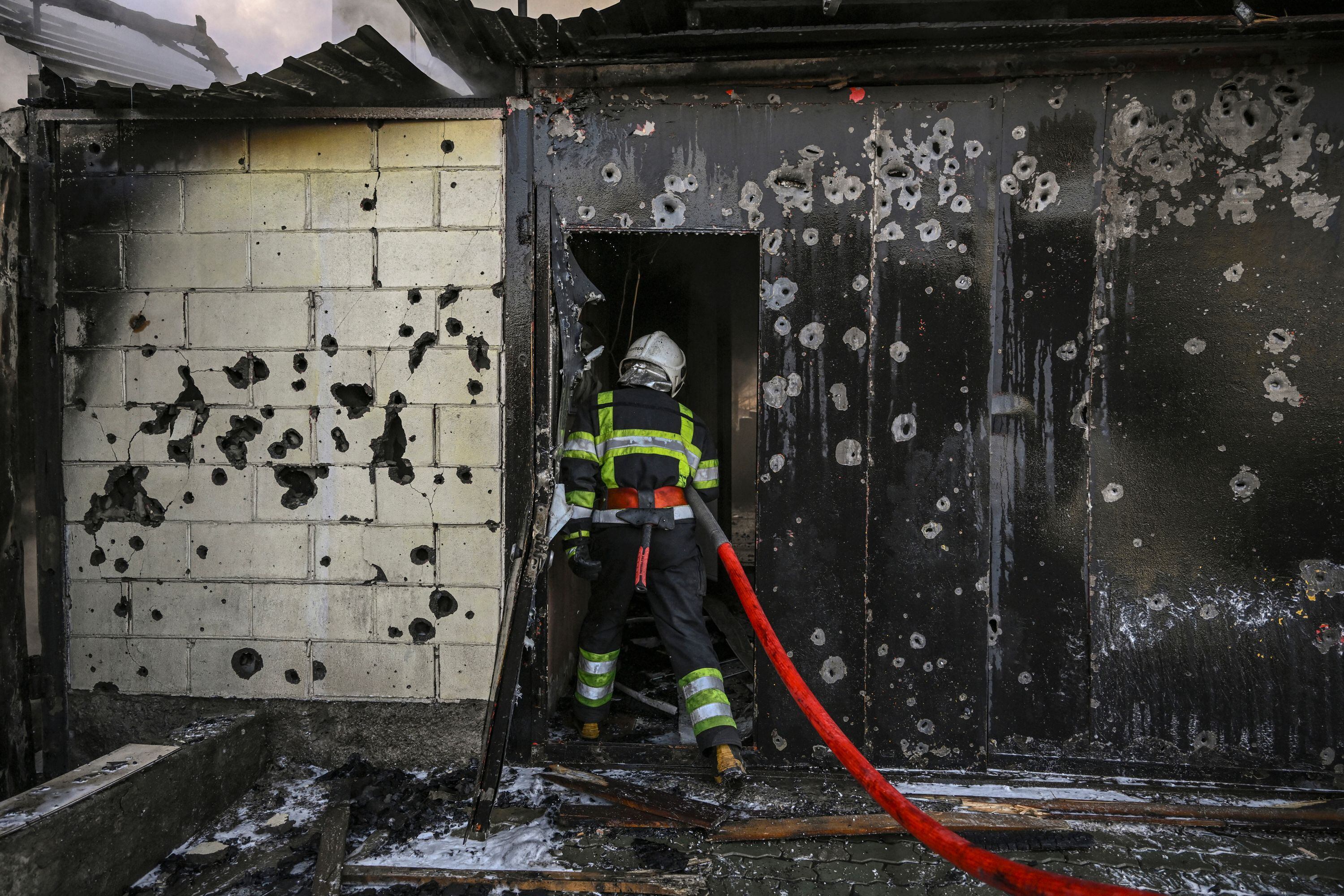 A firefighter enters a house to extinguish a fire after shelling on the 17th day of the Russian invasion of Ukraine, in Kyiv on March 12, 2022. - Russian forces are positioned around Kiev on March 12, 2022 and are "blocking" Mariupol, where thousands of people are suffering a devastating siege, in southern Ukraine, a country that has been bombed for more than two weeks. (Photo by Aris Messinis / AFP) (Photo by ARIS MESSINIS/AFP via Getty Images)