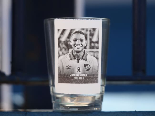 Fotografía que muestra una imagen del fallecido jugador Juan Izquierdo durante un homenaje este miércoles, en Montevideo (Uruguay). Fanáticos del uruguayo Nacional se acercaron hasta la sede del equipo para dejar flores y mensajes al futbolista Izquierdo, quien falleció un día antes en la ciudad brasileña de São Paulo. Debajo de una bandera del conjunto Tricolor que ondea a media asta, los hinchas dejaron camisetas con leyendas escritas de puño y letra. EFE/ Sofía Torres