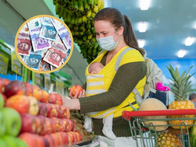 Madre haciendo mercado de frutas mientras carga a su bebé. En el círculo, dinero colombiano (GettyImages)