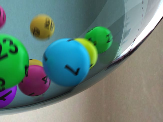 Lottery balls of different colours tumbling in a glass sphere. 3D render with HDRI lighting and raytraced textures.