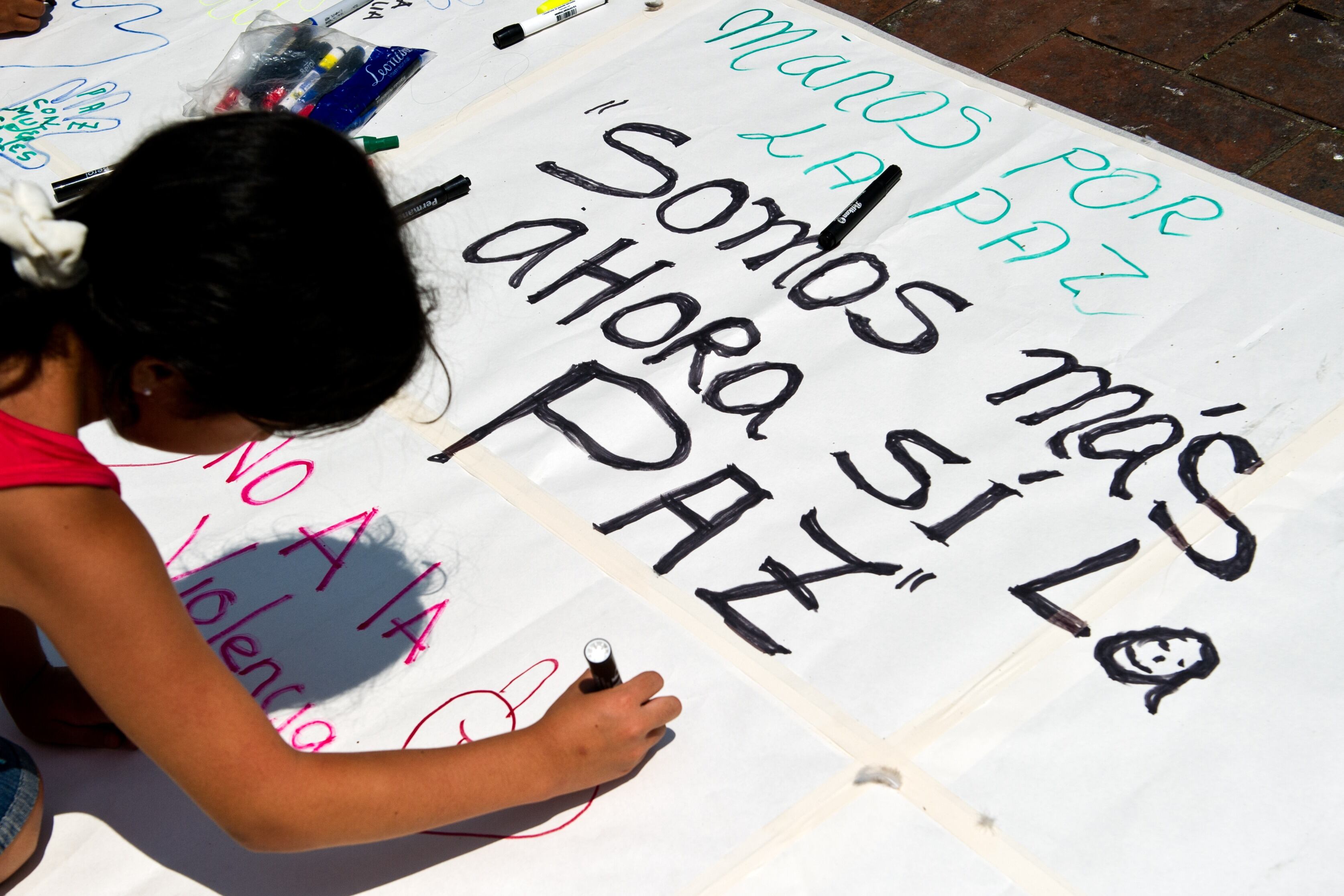 A girl writes on a placard messages alluding to peace on April 9, 2013, in Cali, Valle del Cauca department, Colombia, during a national march in support of the peace process ongoing in Havana between the Revolutionary Armed Forces of Colombia (FARC) guerrillas and the Colombian government . AFP PHOTO/Luis ROBAYO        (Photo credit should read LUIS ROBAYO/AFP via Getty Images)