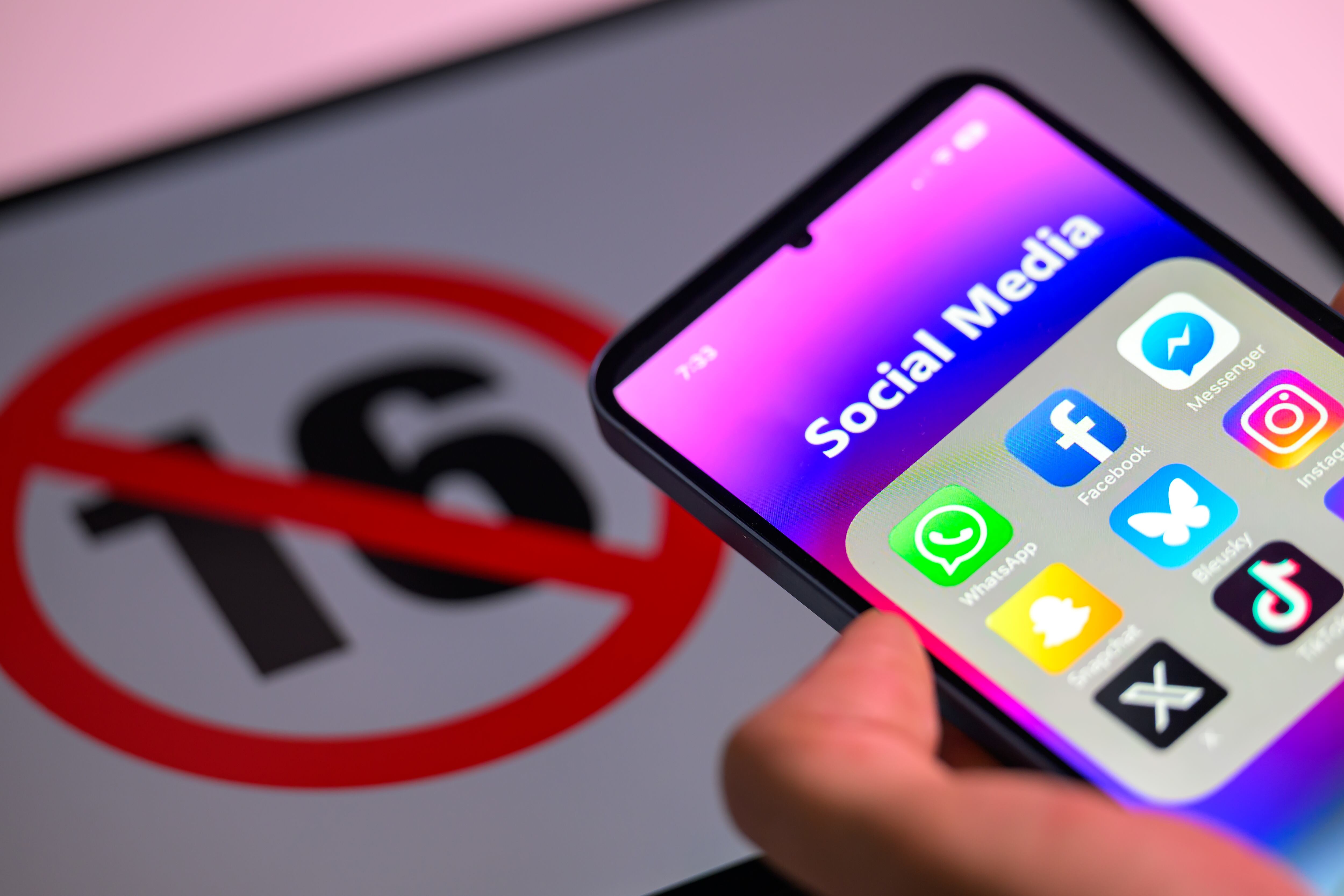 Iconos de redes sociales en la pantalla de un teléfono móvil y otros iconos de medios sociales, con el símbolo de la edad de dieciséis años en el fondo, imagen de referencia.