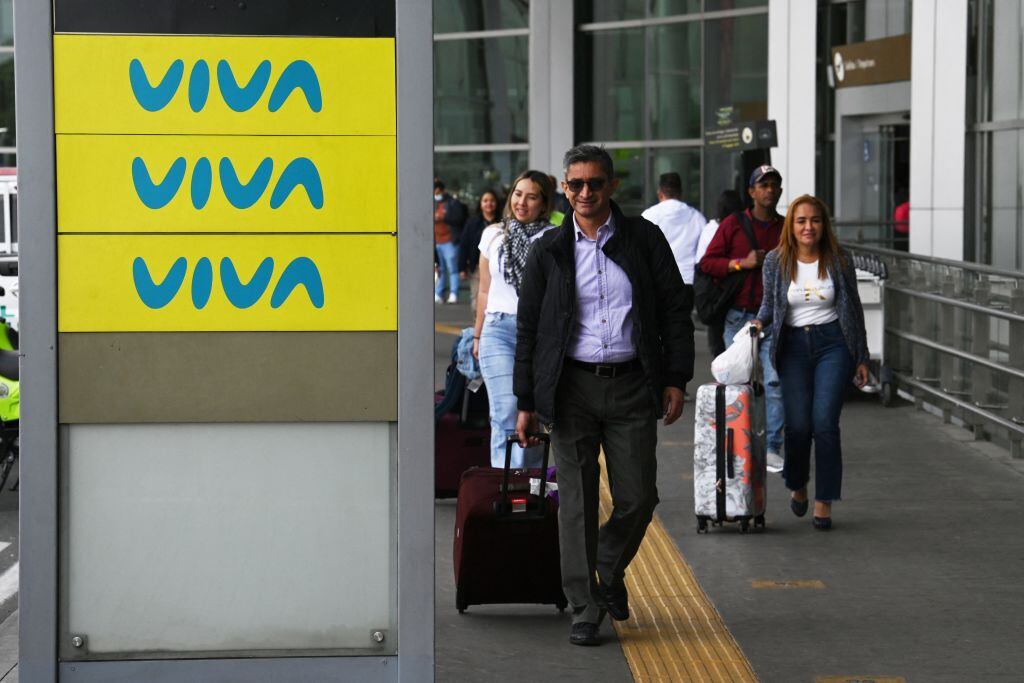 People pass by an advertising board of Viva Air outside the El Dorado international airport in Bogota on February 28, 2023. - The Colombian low-cost airline Viva Air suspended its operations last Monday due to financial problems, according to a company statement. (Photo by Juan Barreto / AFP) (Photo by JUAN BARRETO/AFP via Getty Images)