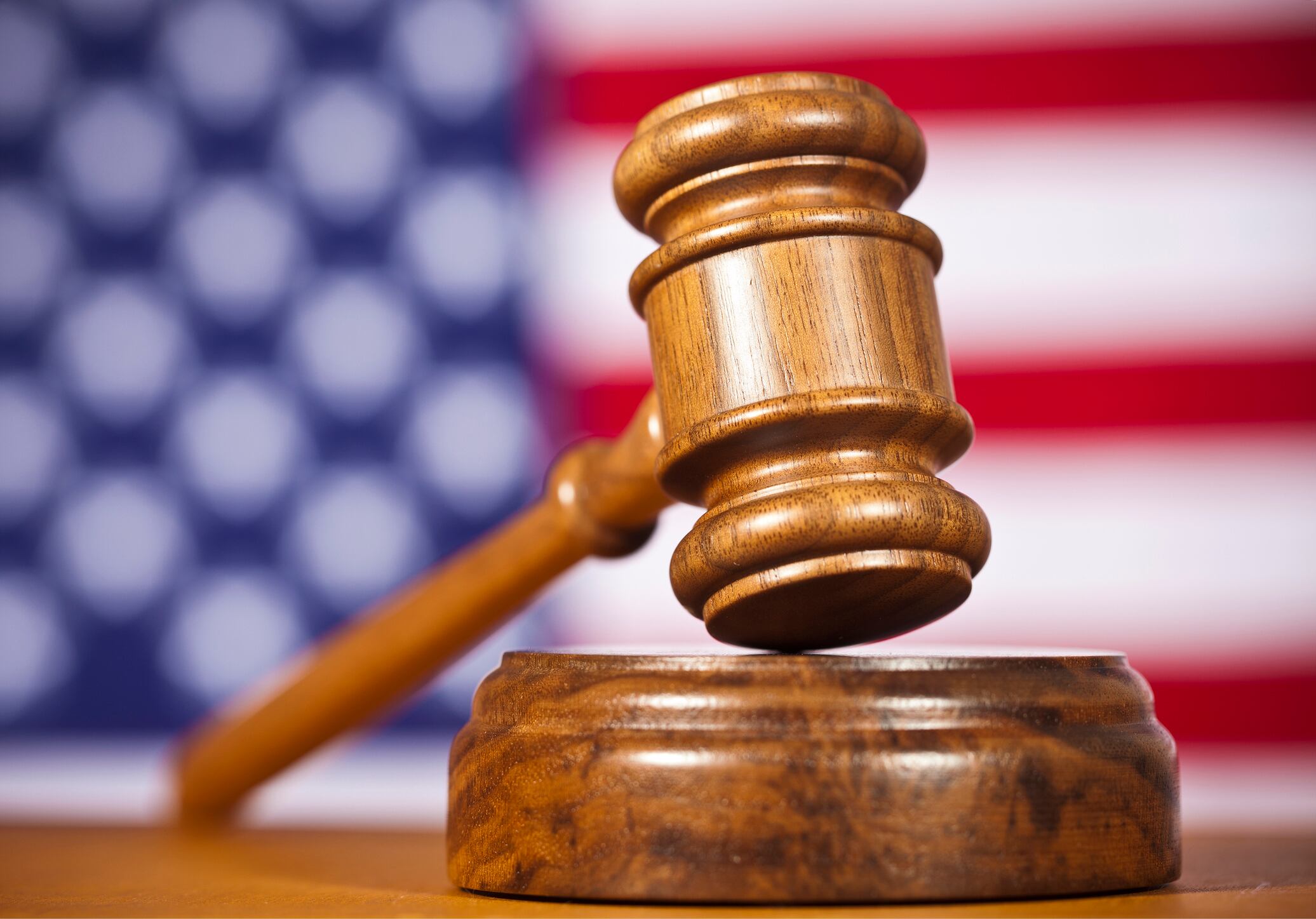 A Wooden Gavel In Front Of An American Flag