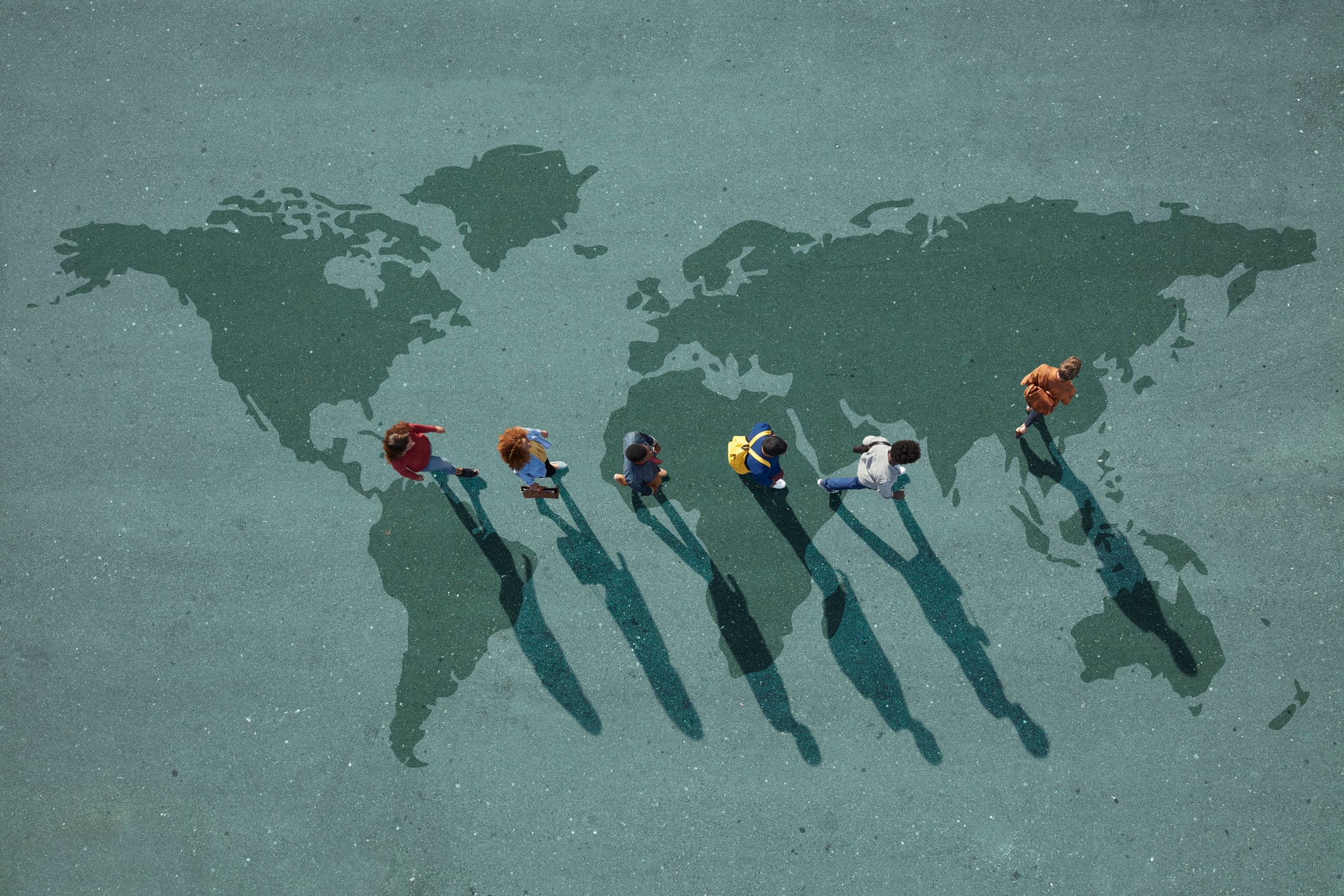 Grupo de personas caminando sobre un mapa del mundo (Getty Images)
