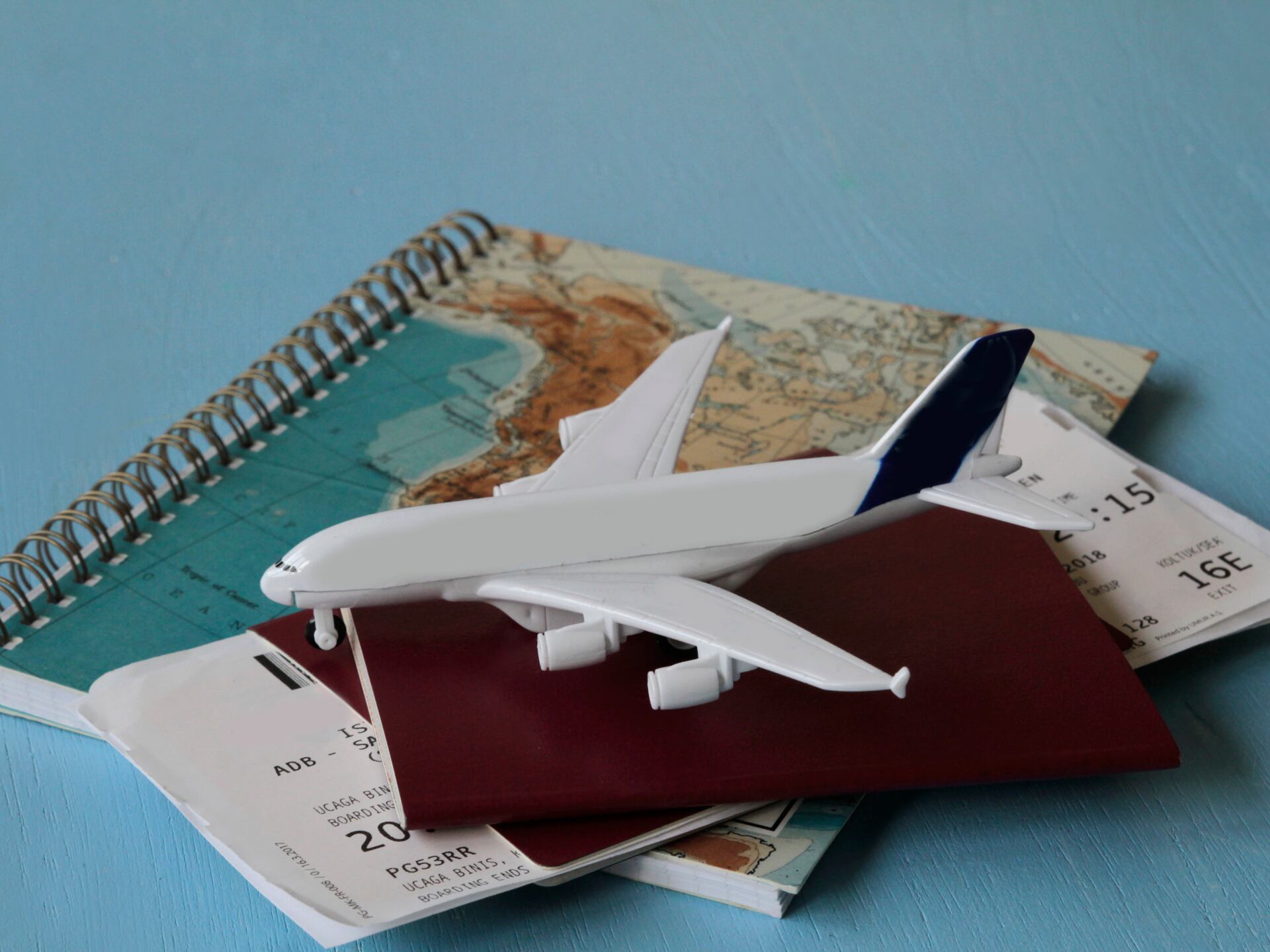 Avión sobre un pasaporte con tiquetes aéreos (Getty Images)