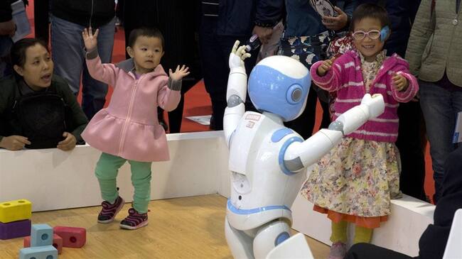 Dos niñas bailan con un robot durante una Conferencia Mundial de Robots en Beijing. Foto: Associated Press - AP - Ng Han Guan
